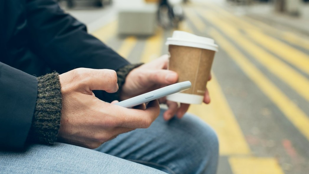 Man holding phone and coffee 16-9