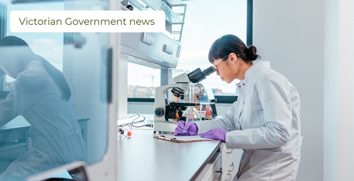 Female scientist looking trough the microscope writing down her discoveries stock photo