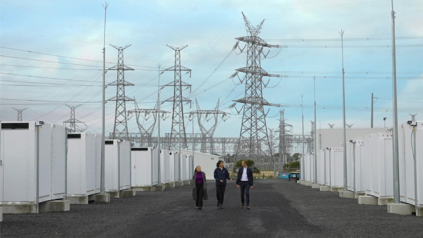 Three people walking in front of a row of power lines
